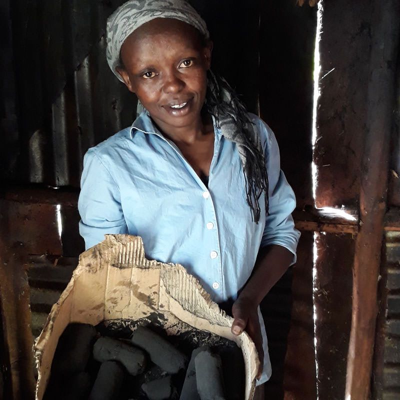 Kenyan tea farmer holding bio briquettes.