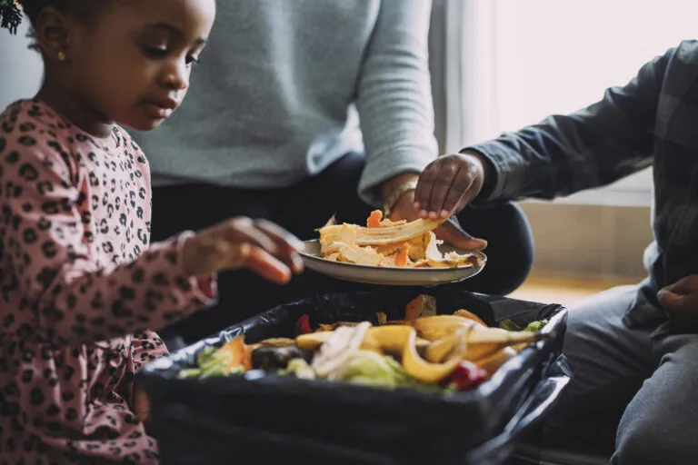 A family making biodegradable compost from vegetable and fruit leftovers as an effort to reduce food waste at home.