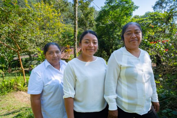 Three women stand side by side smiling
