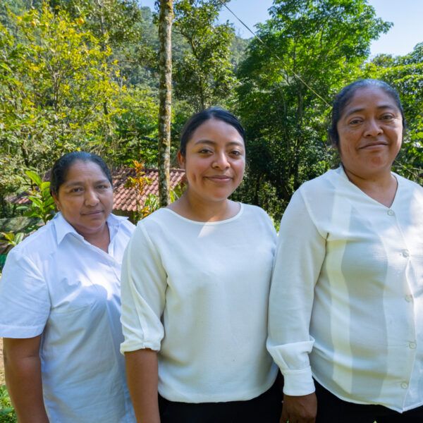 Three women stand side by side smiling