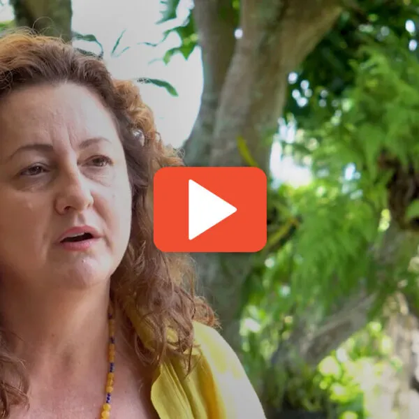 Woman talking in a video thumbnail with a play button.