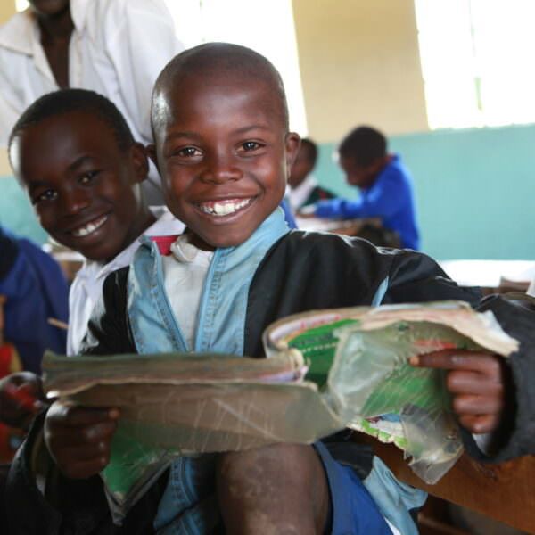 Student at Kericho HQ Primary School smiling while holding a book.