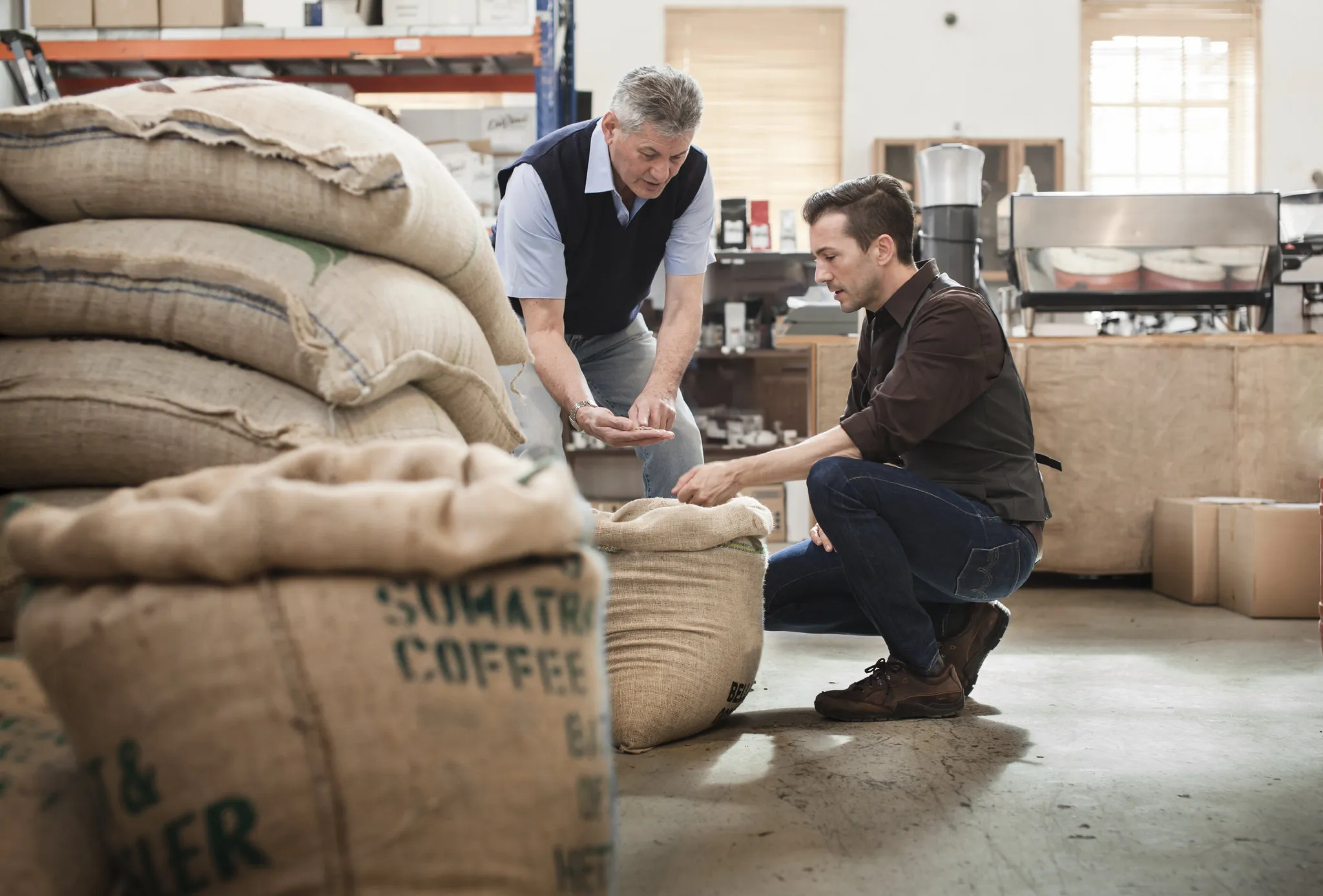 Two people discussing coffee trading with a large bag of coffee in the foreground.