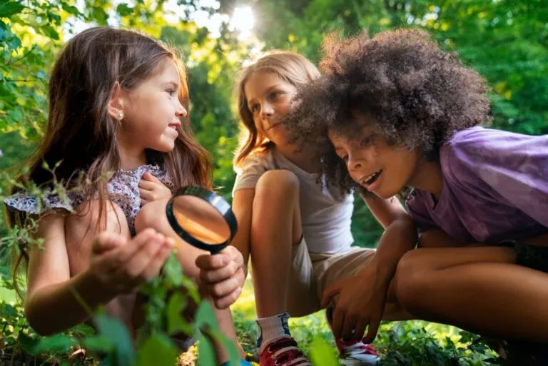 Children examining a plant with a magnifying glass