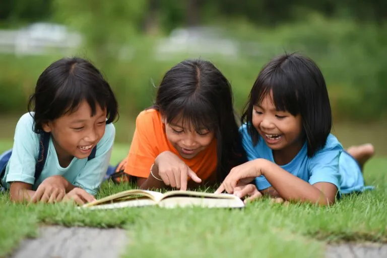 Children lying on the grass reading together