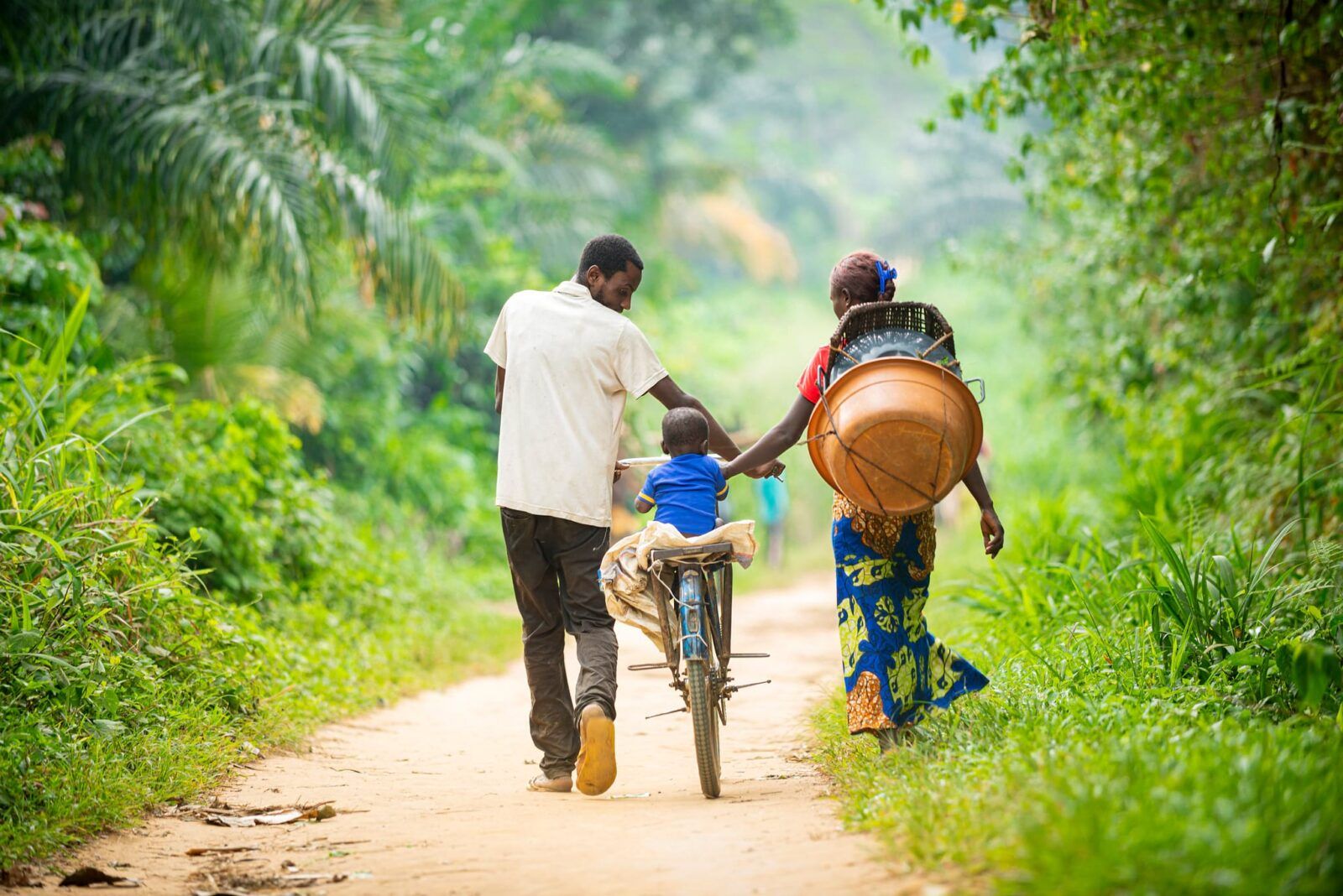 Child riding a bicycle with two adults
