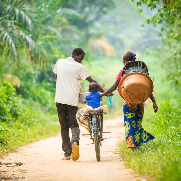 Child riding a bicycle with two adults